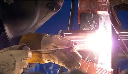 Welder with welding mask, sparks coming from an active weld.